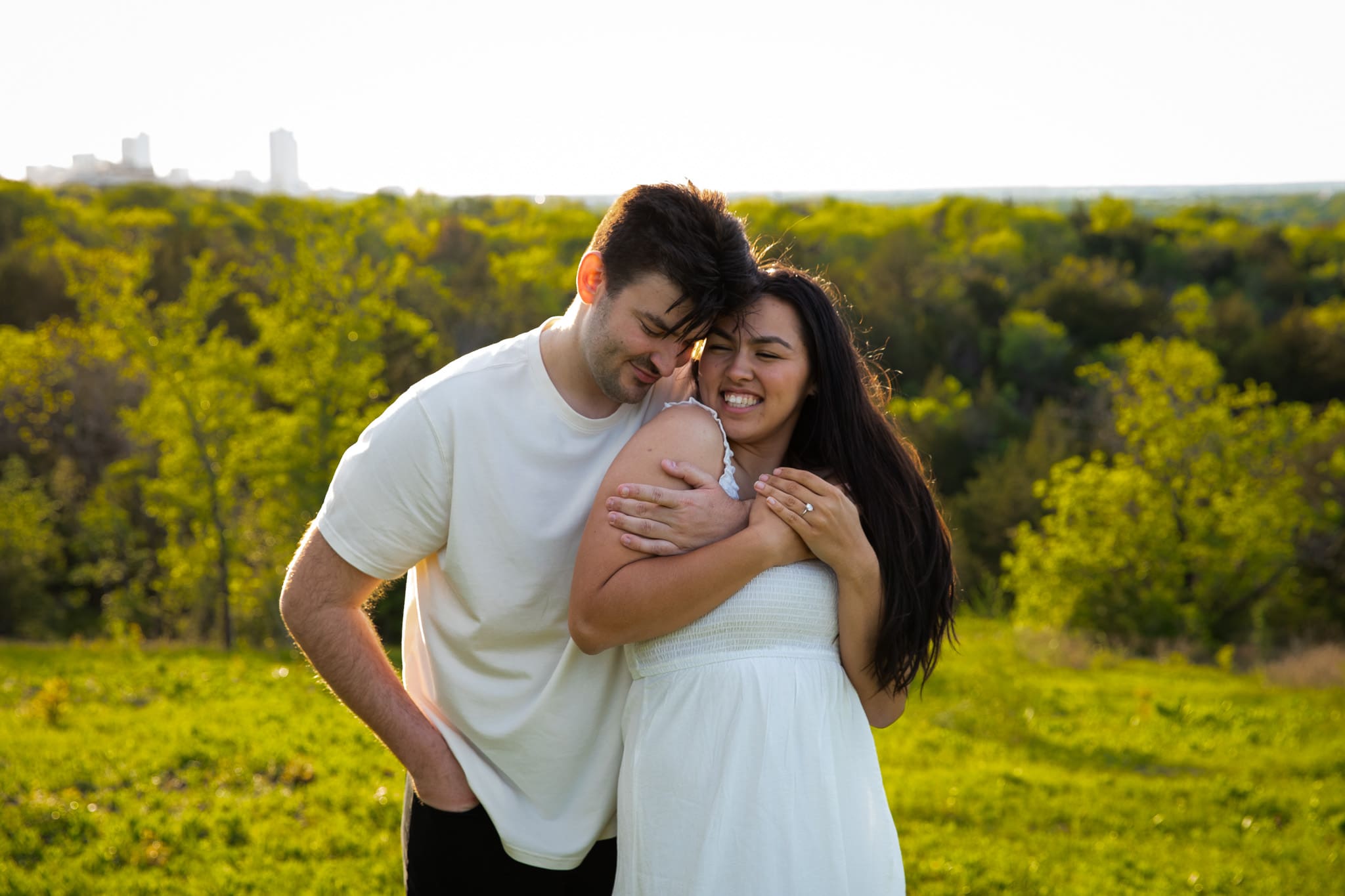 man with his arm around woman in front of green hills