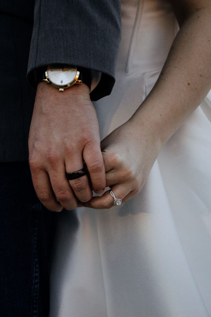 Close up of bride and grooms hands showcasing their wedding rings